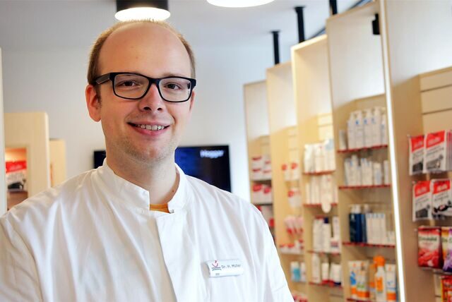 Ein Apotheker steht vor einem Medikamentenregal.