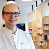 Ein Apotheker steht vor einem Medikamentenregal.