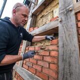 Lehmundo-Chef Aron Keidel mauert die Fassade des Fachwerkhauses mit roten Ziegeln aus.