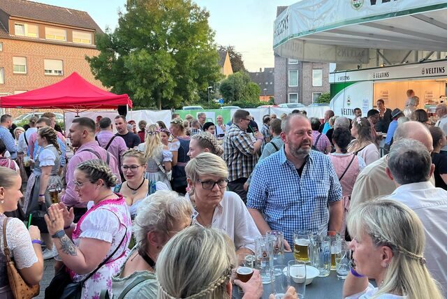 Menschen stehen über den Platz vor dem Feuerwehr verteilt.