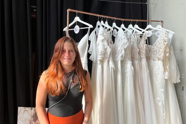 Nadine Seyrek steht neben einer Kleiderstange voller Brautkleider.