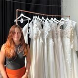 Nadine Seyrek steht neben einer Kleiderstange voller Brautkleider.