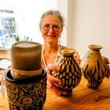 Anja Speker steht in ihrer Töpferwerkstatt und präsentiert Vasen.