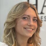 Giuliana Koke und Jana Sparka stehen in dem Salon. Die Mitarbeiterin hält ein Hinweisschild in der Hand, welches über die bargeldlose Zahlung informiert. Die Saloninhaberin zeigt auf das Schild.