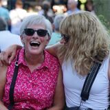 Zwei Frauen sitzen bei der Veranstaltung After Work Waltrop nebeneinander. Die linke Frau lacht in die Kamera, die rechte legt den Arm um ihre Nachbarin und lacht sie dabei an.