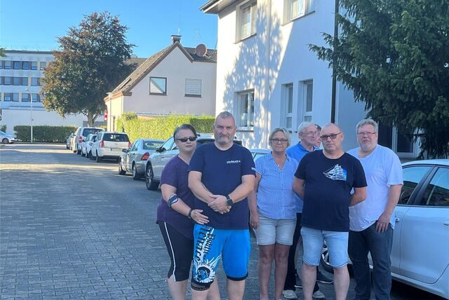 Anwohner stehen Im Ternäckern vor einer Schlange parkender Autos.