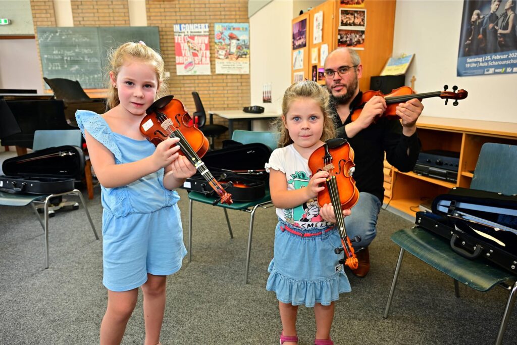 Tag der offenen Tür der städtischen Musikschule: Laura und Luisa Friedenstab probieren sich an der Geige, Dozent Gerarto Gramajo leitet sie an.