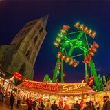 Ein Imbissstand und ein Fahrgeschäft stehen beim Stunikenmarkt in Hamm vor der Pauluskirche.