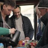 Mehrere Menschen stehen an einem Tisch mit Snacks und Getränken.