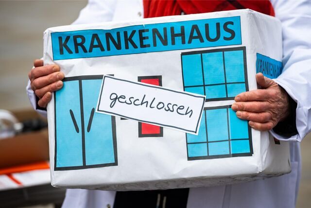 Bei einer Aktion des Bündnisses Klinikrettung und Gemeingut in BürgerInnenhand (GiB) e.V. hält eine Frau eine Kiste mit der Aufschrift „„Krankenhaus geschlossen““.