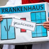 Bei einer Aktion des Bündnisses Klinikrettung und Gemeingut in BürgerInnenhand (GiB) e.V. hält eine Frau eine Kiste mit der Aufschrift „„Krankenhaus geschlossen““.