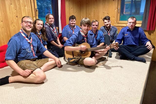 Die Pfadfinder Yannick Schenker, Amelie Burchard, Marie Rothe, Felix Kriehn, Jakob Oelmann, Marlon Gerlach, Nils Steiner und Tobias Aeling (von links) sitzen in ihrer Hütte auf einem Podest. Oelmann hält eine Gitarre in den Händen-
