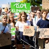 Mehrere junge Menschen halten Schilder in der Hand. Besonders auffällig in der Menge ist ein grünes Schild mit der Aufschrift „Klimastreik 15.09.“.