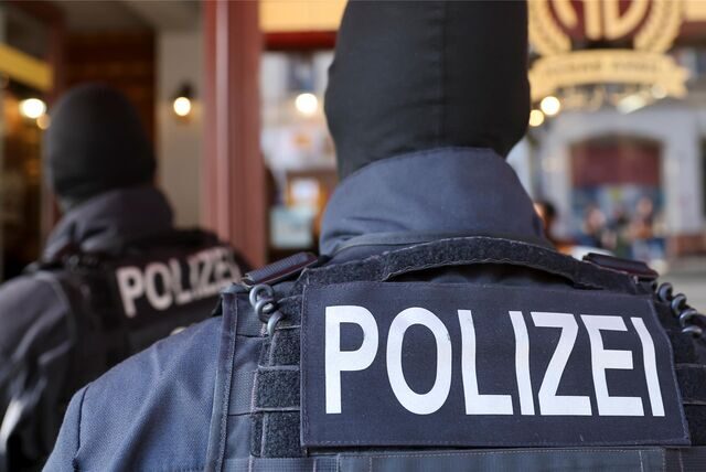 Zwei Polizisten in schwarzer Einsatzkleidung von hinten