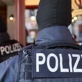Zwei Polizisten in schwarzer Einsatzkleidung von hinten