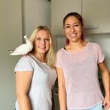 Zwei junge Frauen, wovon eine eine Taube auf der Schulter trägt.