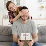 mann wird mit einem geschenk von einer frau überrascht