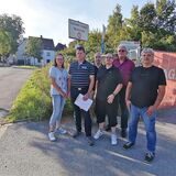 Anwohnergruppe vor einem offenen Bauzaun an der ehemaligen Kraftwerks-Zufahrt in Dortmund-Oestrich.