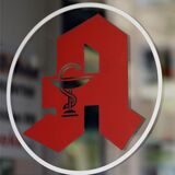 Ein Fenster mit einem Apotheken-Zeichen ist zu sehen. Daneben hängt ein Schild mit der Aufschrift: „Apotheke heute geschlossen.“