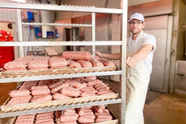 Ein Fleischer, der einen Wagen mit Wurstwaren schiebt.