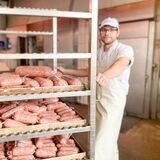 Ein Fleischer, der einen Wagen mit Wurstwaren schiebt.