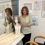 Friseurin Ingrid Frings steht in ihrem Recklinghäuser Salon neben einem Puppenkopf mit Perücke und blickt traurig in die Kamera.