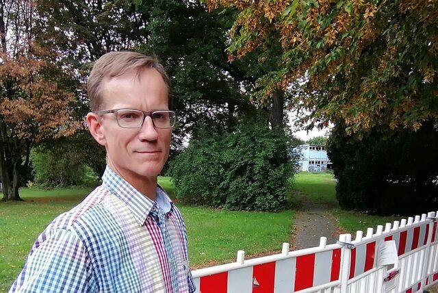 Schulleiter Ulrich Gerdesmeyer auf dem abseits gelegenen Teil des Schulareals mit dem abgebrannten Pavillon im Hintergrund.