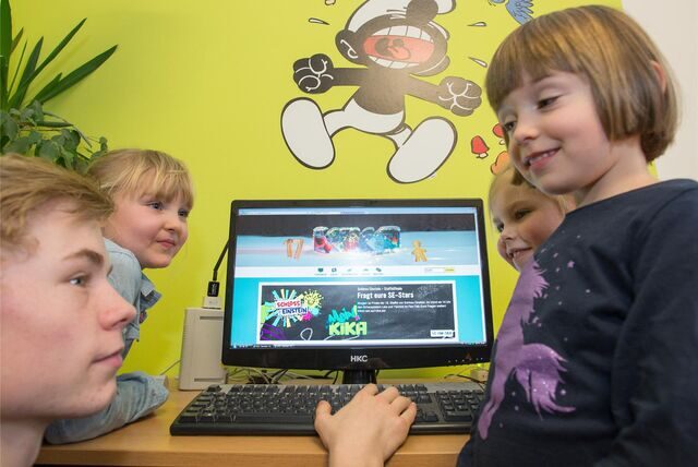 Der FSJ-ler Tom-Martin Schmidt mit den Kindern (l-r) Lotta, Lena und Christa an einem Computer am 17.12.2015 in Halle (Sachsen-Anhalt).
