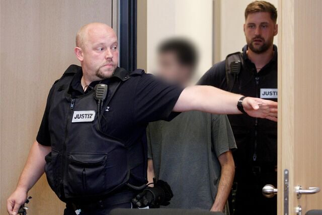 Der Hauptangeklagte im Prozess um einen Garagen-Mord wird von Justizbeamten in den Gerichtssaal geführt. Der Hauptangeklagte ist ein 27 Jahre alter Mann aus Dortmund, der am 07.03.2023 nach einem Streit im Straßenverkehr einen Mann aus Bochum in dessen Auto in einer Tiefgarage erschossen haben soll.