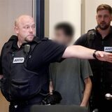 Der Hauptangeklagte im Prozess um einen Garagen-Mord wird von Justizbeamten in den Gerichtssaal geführt. Der Hauptangeklagte ist ein 27 Jahre alter Mann aus Dortmund, der am 07.03.2023 nach einem Streit im Straßenverkehr einen Mann aus Bochum in dessen Auto in einer Tiefgarage erschossen haben soll.