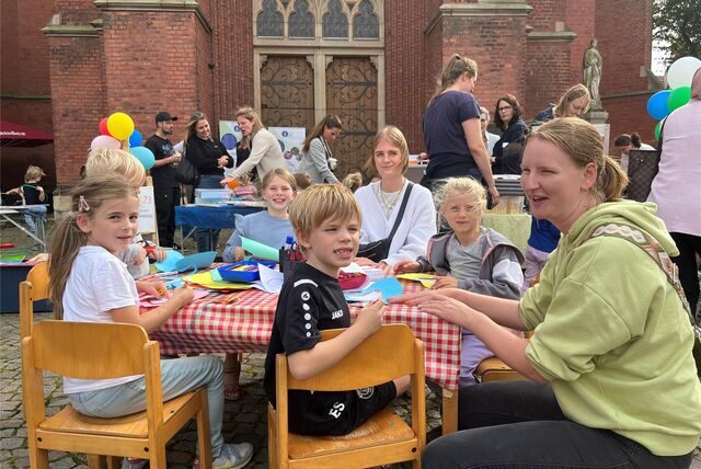 Kinder sind um einen Tisch versammelt, um zu malen.