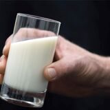 Ein Mann hält ein Glas Milch in der Hand.