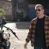 Sylvester Stallone steht neben einem Motorrad und hat eine Sonnenbrille auf.