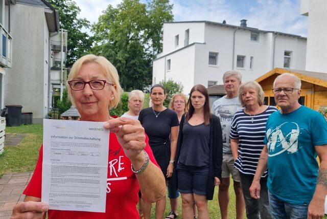 Eine Frau zeigt vor einer Gruppe Menschen ein Schriftstück