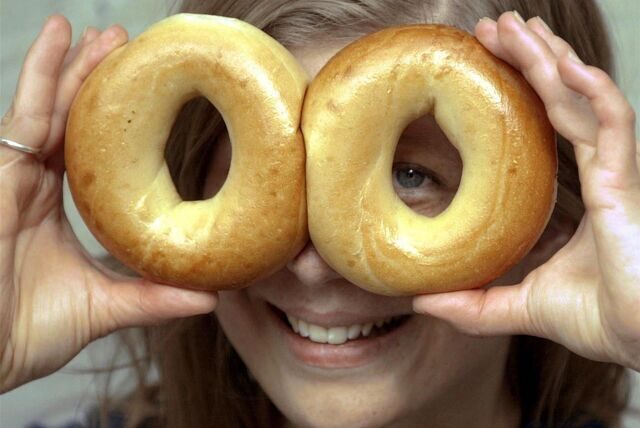 Eine Frau hält sich zwei Bagel vors Gesicht.
