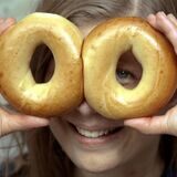 Eine Frau hält sich zwei Bagel vors Gesicht.