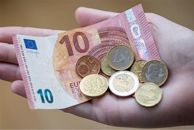 10€-Schein und einige Euro-Münzen in einer Hand