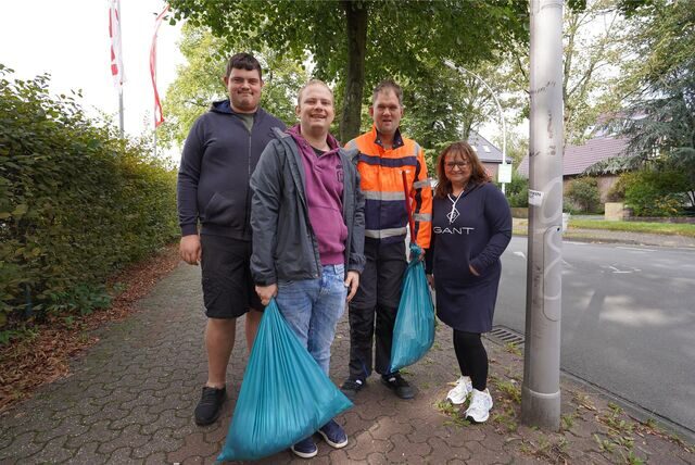 Vier Menschen mit Müllsäcken