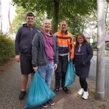 Vier Menschen mit Müllsäcken