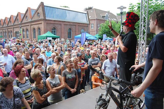 Menschen stehen vor einer Bühne, auf der gerade ein Fahrrad versteigert wird.