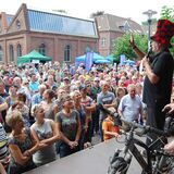 Menschen stehen vor einer Bühne, auf der gerade ein Fahrrad versteigert wird.