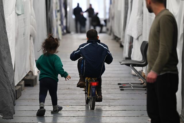 Aufnahme aus einer Flüchtlingsunterkunft: Kinder laufen über einen Gang. Ein Mann schaut ihnen nach.
