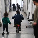 Aufnahme aus einer Flüchtlingsunterkunft: Kinder laufen über einen Gang. Ein Mann schaut ihnen nach.