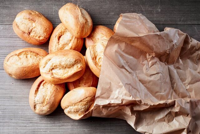 Brötchen rollen aus einer Papiertüte auf den Tisch.
