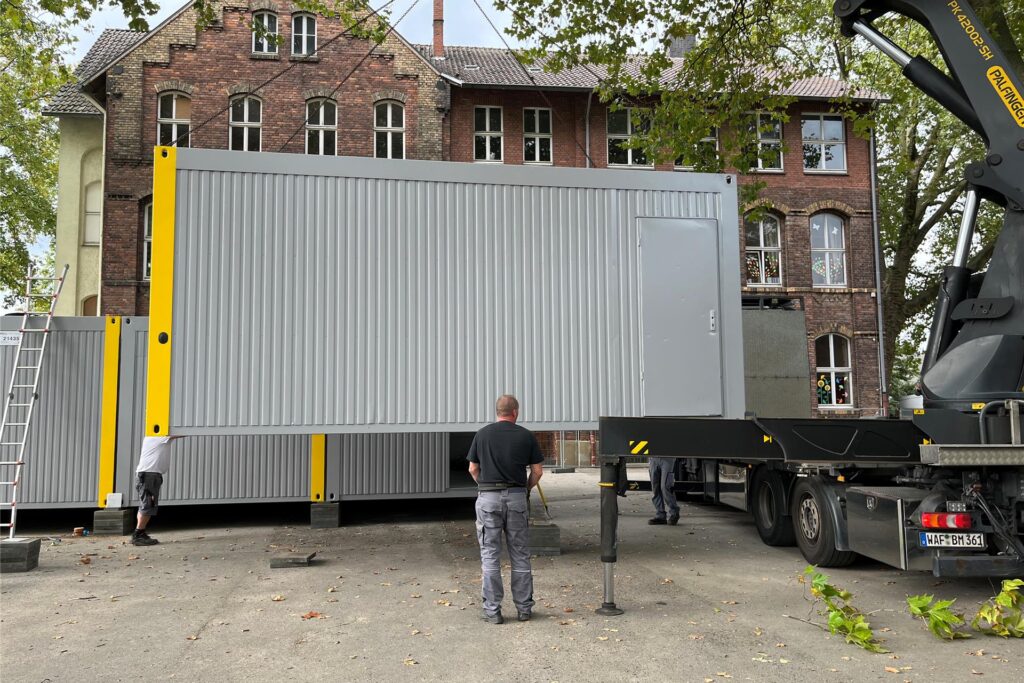 Ein Lkw-Fahrer hebt mit Hilfe eines Krans die einzelnen Container vom Lkw. Ein Lkw-Fahrer hebt mit Hilfe eines Krans die einzelnen Container vom Lkw.