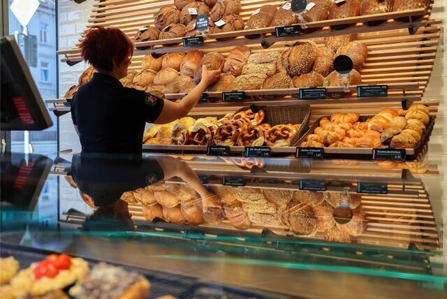 Eine Mitarbeiterin räumt Mischbrot in die Auslage einer Bäckerei.