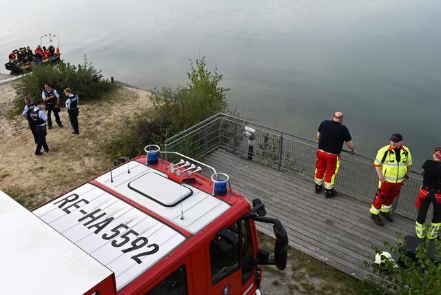 Feuerwehrleute, Polizeibeamte und Taucher in einem Boot halten sich am Ufer des Silbersees II auf.