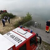 Feuerwehrleute, Polizeibeamte und Taucher in einem Boot halten sich am Ufer des Silbersees II auf.