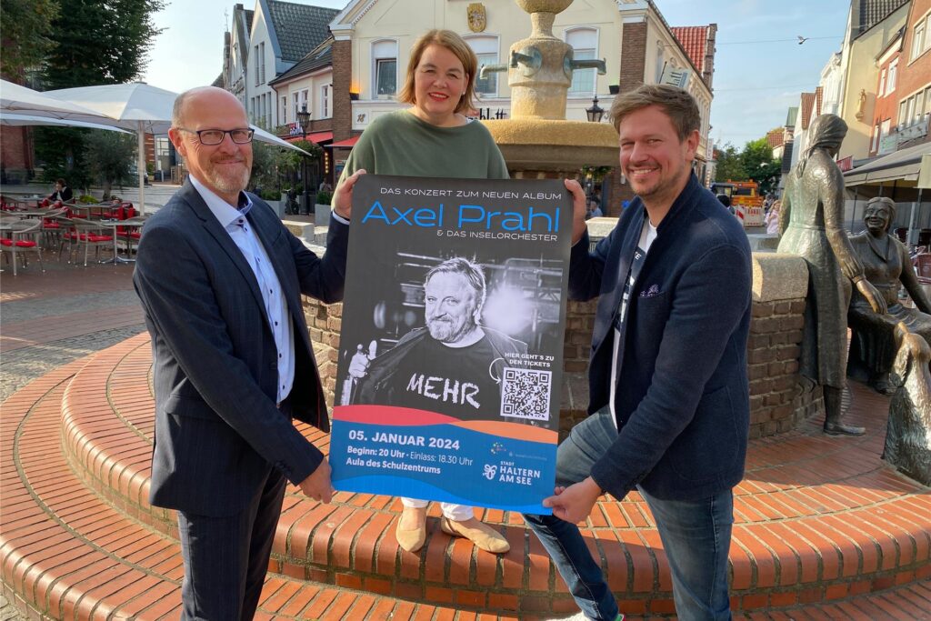 Zwei Männer und eine Frau stehen vor einem Brunnen und halten ein Plakat hoch. Auf diesem ist Tatort-Schauspieler Axel prahl zu sehen. Zwei Männer und eine Frau stehen vor einem Brunnen und halten ein Plakat hoch. Auf diesem ist Tatort-Schauspieler Axel prahl zu sehen.
