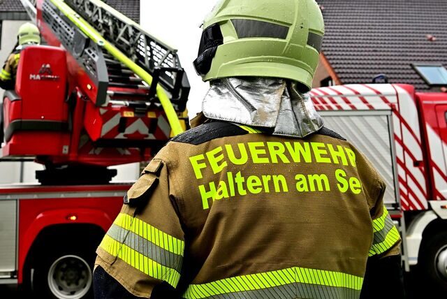 Ein Feuerwehrmann steht an einem Einsatzfahrzeug.